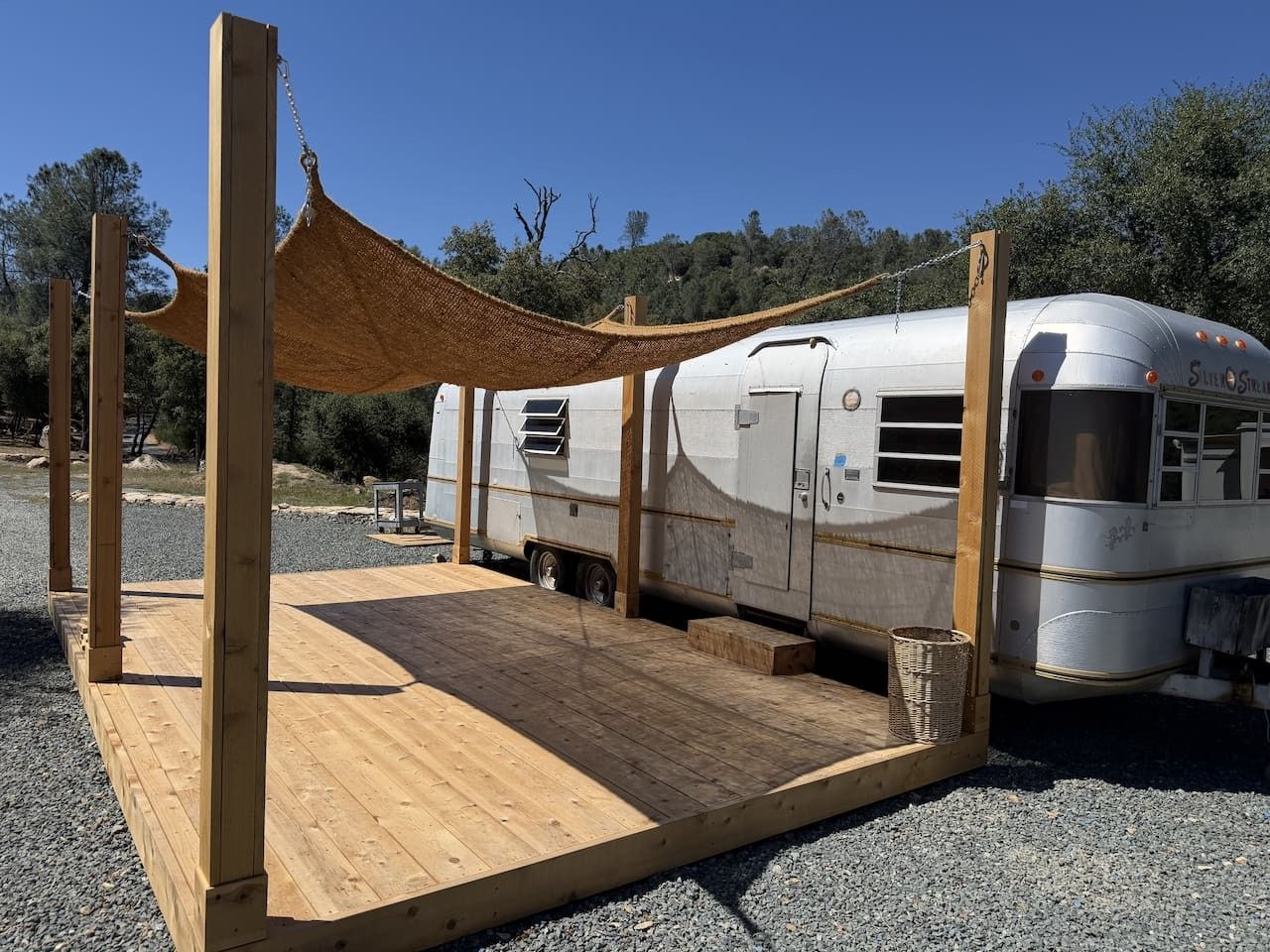 A stationary RV with a wooden deck and a canopy structure.