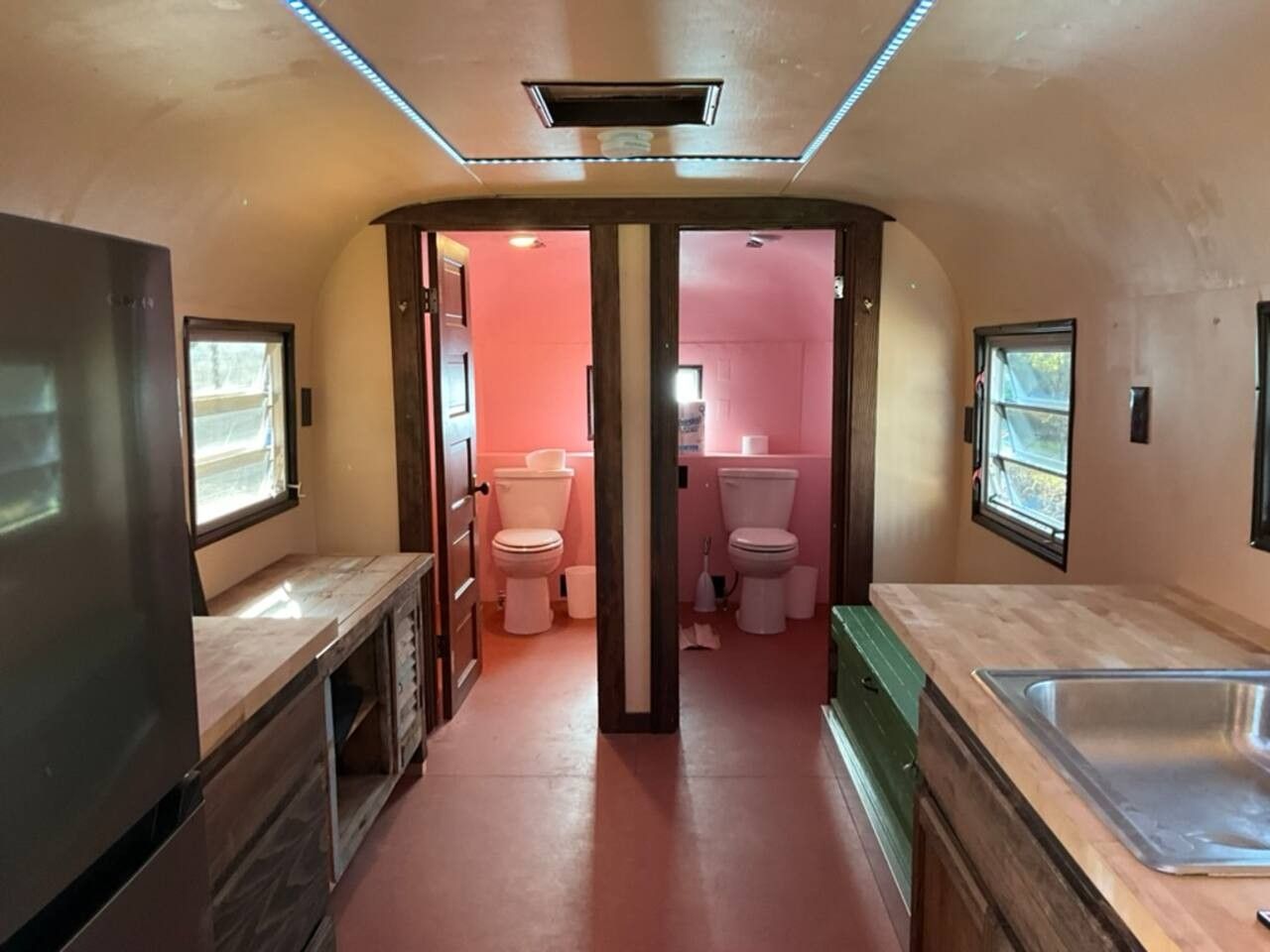 Une petite salle de bain comprenant deux toilettes, un lavabo et un espace douche.