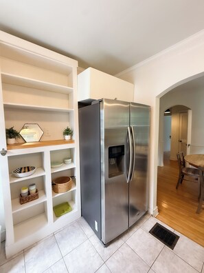 A kitchen with a stainless steel refrigerator, white cabinetry, and a dining area with a wooden table and chairs. - Cozy and Convenient - Retreat on Rosemont - Kid Friendly - Covered Back Deck (Lexington)