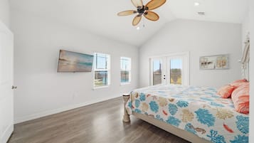 A bedroom with a bed, a ceiling fan, a painting, and a window with blinds.