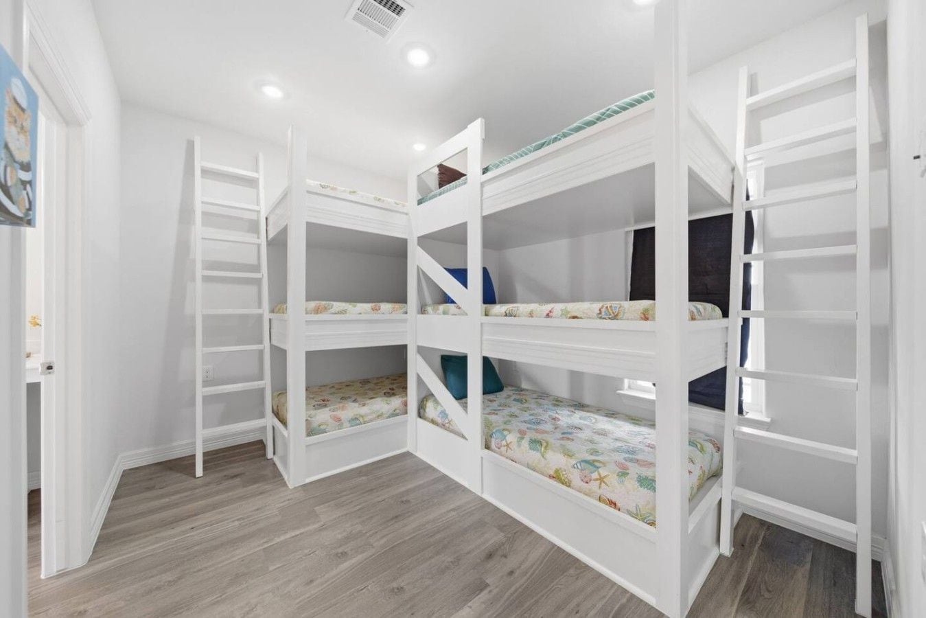 Ein Zimmer mit Etagenbetten, Holzboden und weißen Wänden.