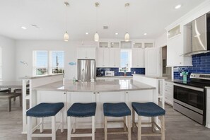 A modern kitchen with a central island, white cabinetry, and a blue backsplash. - Surfside Beach • Steps To Beach • Relax • Enjoy (Surfside Beach)