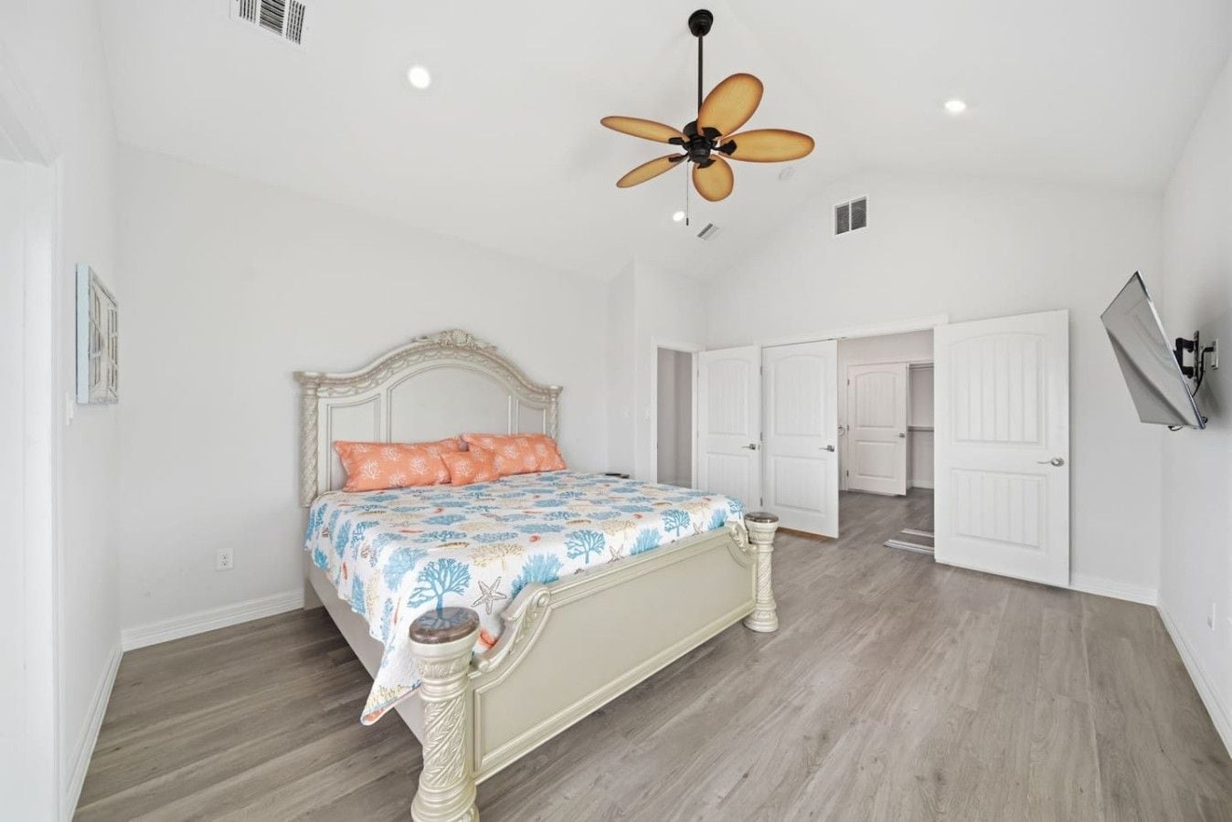 A bedroom with a bed, a ceiling fan, and a door leading to another room.