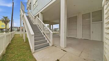 A residential building with a covered porch, a staircase, and a garage with closed doors.