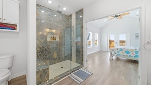 Een moderne badkamer met een douchecabine van glas, een toilet en een wastafel met een plankje.
