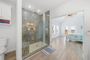 A modern bathroom with a glass-enclosed shower, a toilet, and a vanity with a shelf. - Surfside Beach • Steps To Beach • Relax • Enjoy (Surfside Beach)