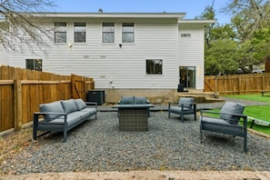 A residential building with a patio area featuring outdoor furniture and a fire pit.