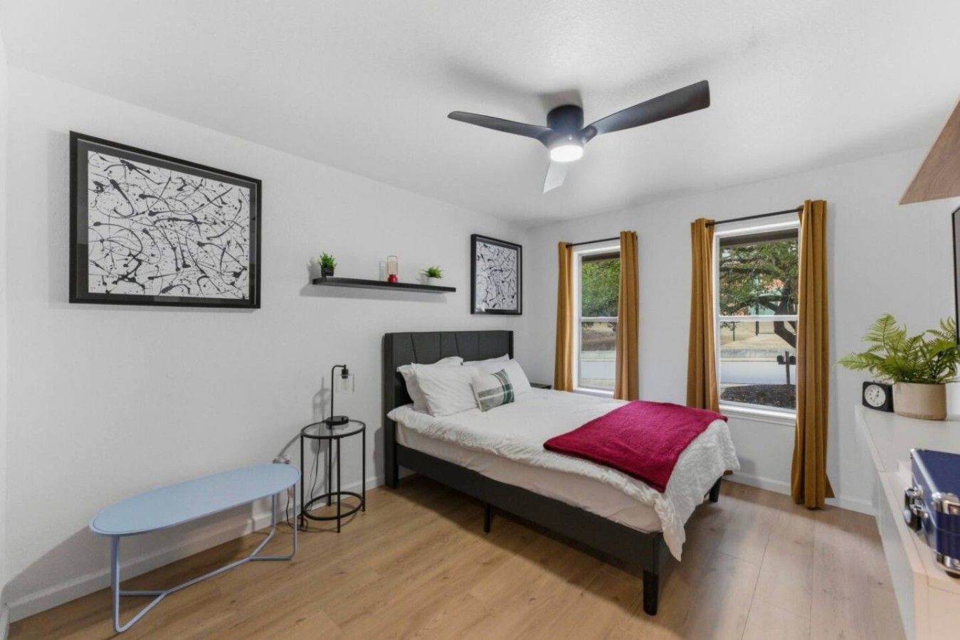 A modern bedroom with a bed, bedside table, and a ceiling fan.
