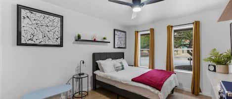 Un dormitorio moderno con cama, mesita de noche y ventilador de techo.