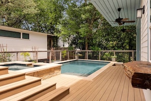 Ein Garten mit Swimmingpool, Holzterrasse und einem umzäunten Bereich.