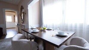 Ein Esszimmer mit einem Holztisch, gedeckt für vier Personen, weißen Stühlen und Blick auf einen Flur.