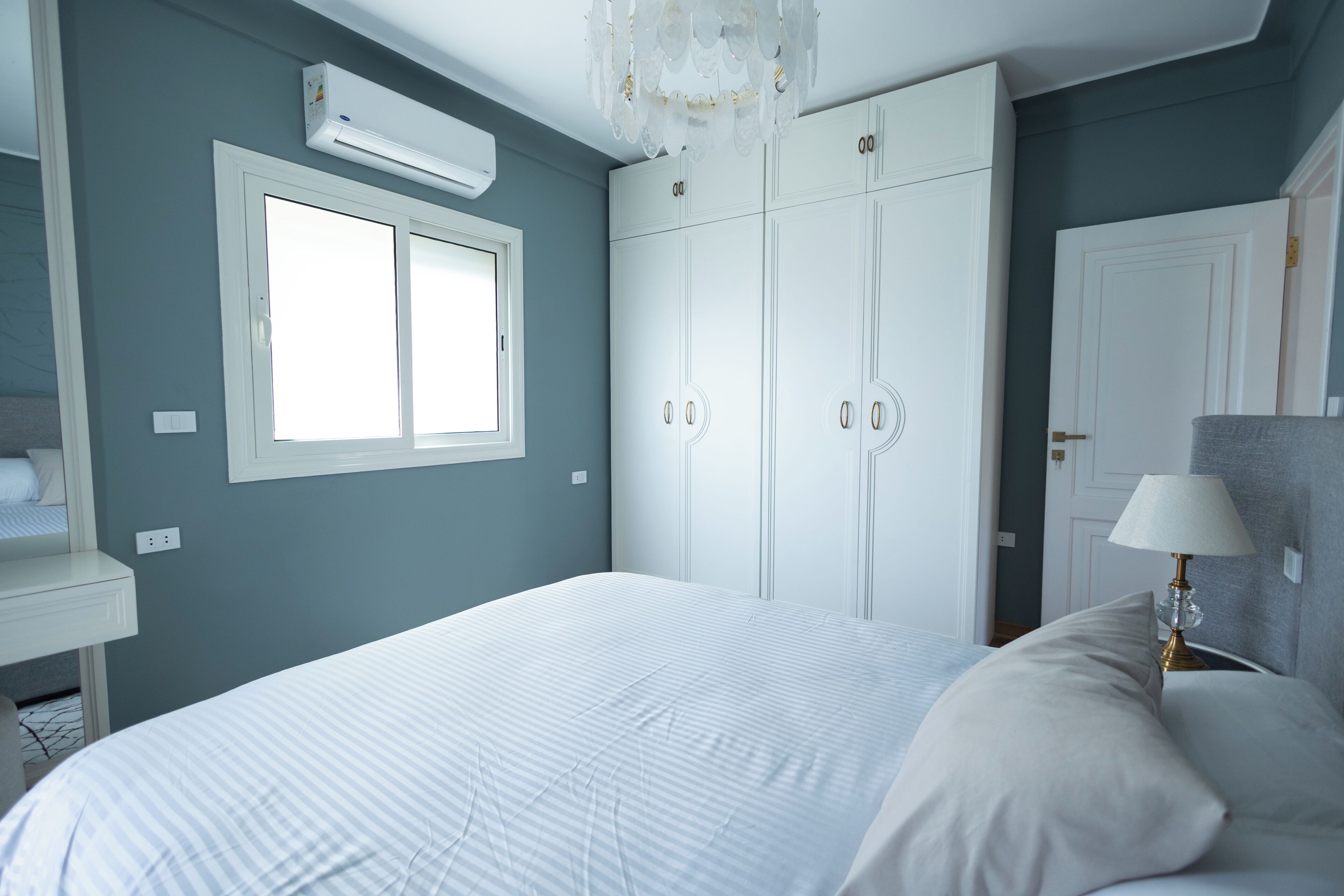 Ein Schlafzimmer mit Bett, Kleiderschrank, Fenster und Lampe.