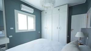 Ein Schlafzimmer mit Bett, Kleiderschrank, Fenster und Lampe.