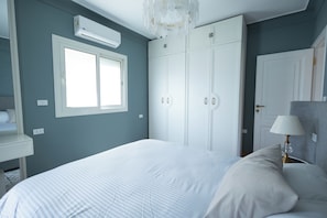 Ein Schlafzimmer mit Bett, Kleiderschrank, Fenster und Lampe.