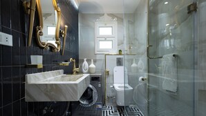 Ein modernes Badezimmer mit einem мраморный Waschtisch, einer Glasdusche und einer Toilette.