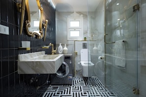 Ein modernes Badezimmer mit einem мраморный Waschtisch, einer Glasdusche und einer Toilette.