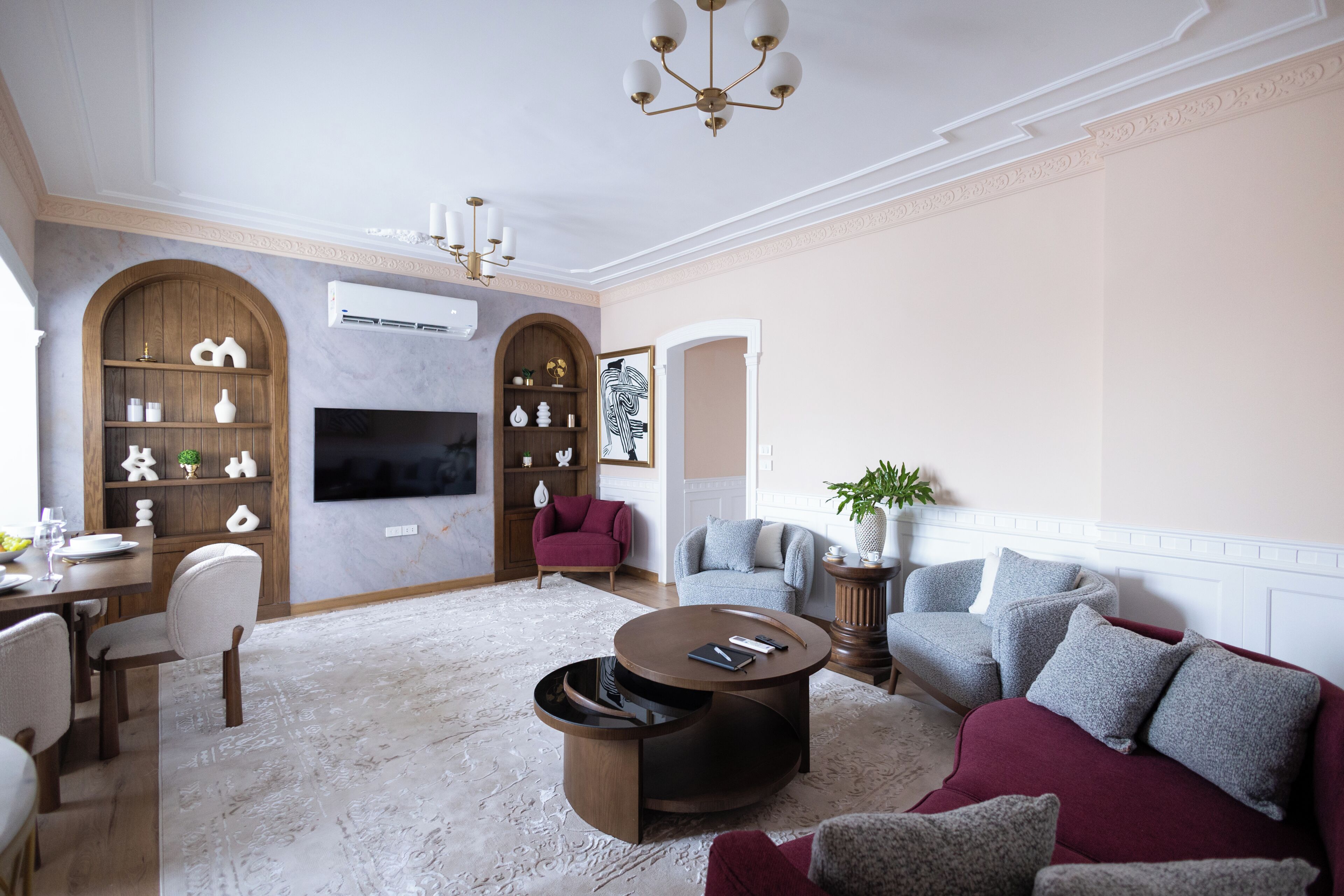 A modern living room with a round coffee table, a television, and a fireplace.