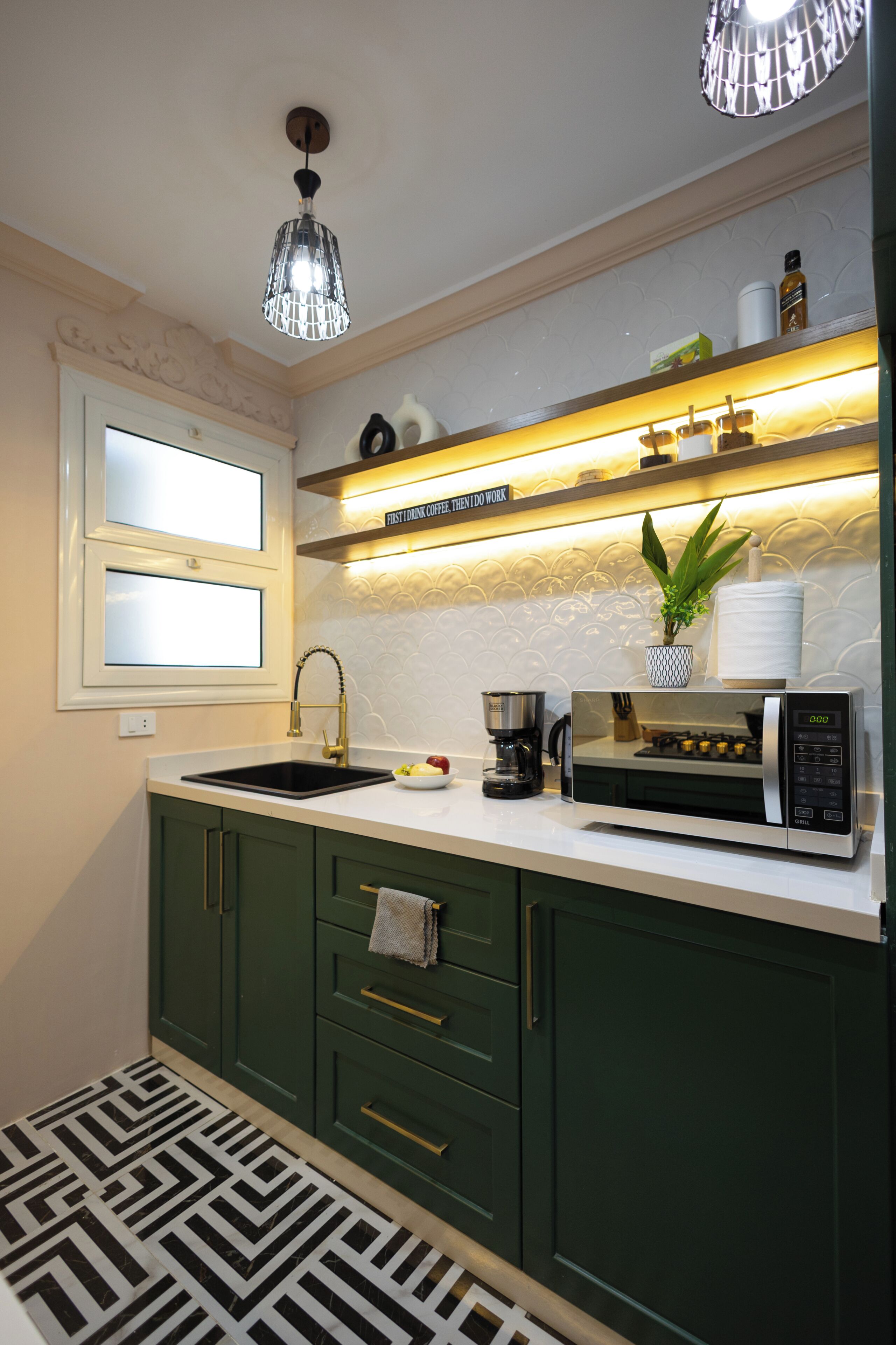 A modern kitchen with a sink, a coffee maker, a microwave, and a shelf with kitchen items.