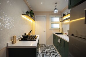 A compact kitchen with a gas stove, a sink, and a refrigerator. - Sunny Zamalek 2-Bedroom/2Bath Apartment with Side Nile View (Giza Governorate)
