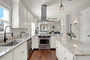 A modern kitchen with white cabinetry, a stainless steel range, and a marble countertop. - New Thunderbolt Cottage on Harris Street Less than 4 Miles from Forsyth Park! (Savannah)