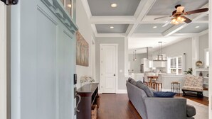 A spacious living area with a gray sofa, a dining table, and a kitchen in the background. - New Thunderbolt Cottage on Harris Street Less than 4 Miles from Forsyth Park! (Savannah)