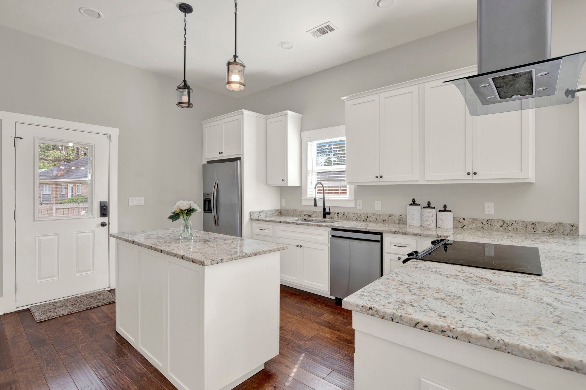 A modern kitchen with white cabinetry, granite countertops, and stainless steel appliances.