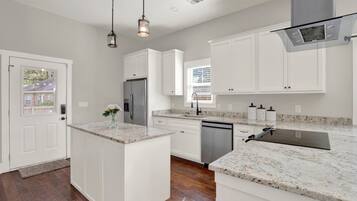 A modern kitchen with white cabinetry, granite countertops, and stainless steel appliances.