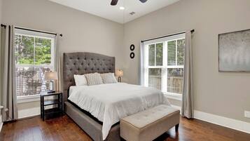 A bedroom with a large bed, a bench, a nightstand, and a ceiling fan.