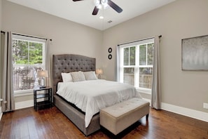 A bedroom with a large bed, a bench, a nightstand, and a ceiling fan. - New Thunderbolt Cottage on Harris Street Less than 4 Miles from Forsyth Park! (Savannah)