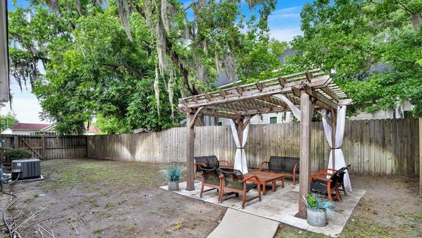 A backyard with a wooden pergola, outdoor furniture, and a concrete pathway. - New Thunderbolt Cottage on Harris Street Less than 4 Miles from Forsyth Park! (Savannah)