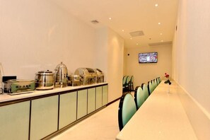 A hotel dining area with a long table, chairs, and a buffet station with various food items. - (Guangzhou)