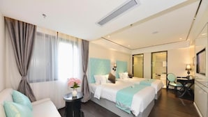 A hotel room with two beds, a sofa, a desk, and a chair. - (Guangzhou)