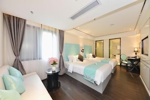 A hotel room with two beds, a sofa, a desk, and a chair. - (Guangzhou)