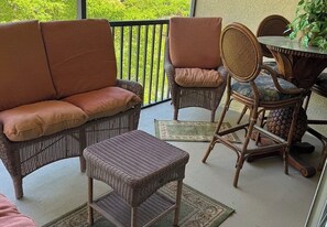 A balcony with wicker furniture, including a sofa, chairs, and a small table. - Paradise awaits! Straight shot to the beach! Close to all Naples has to offer! (Naples)