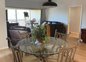 A dining area with a glass table surrounded by metal chairs, a potted plant, and a black pendant light. - Paradise awaits! Straight shot to the beach! Close to all Naples has to offer! (Naples)