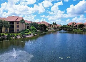 A hotel with a water feature in the foreground, surrounded by greenery and a clear sky. - Paradise awaits! Straight shot to the beach! Close to all Naples has to offer! (Naples)