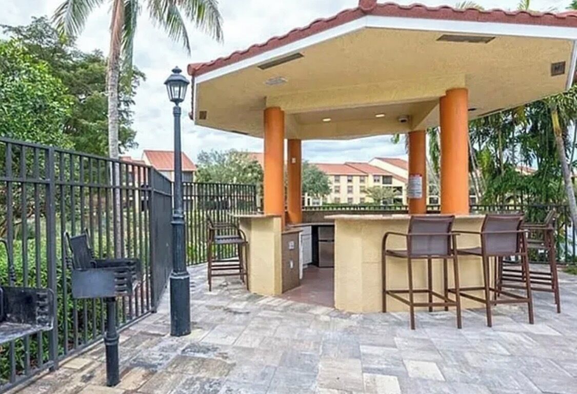 Une terrasse extérieure dotée d’un espace salon couvert, d’une poubelle et d’un lampadaire.