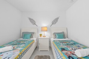 Ein Doppelzimmer mit zwei Betten, einem Nachttisch mit Lampe und dekorativer Wandgestaltung.