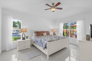 A bedroom with a bed, bedside lamps, a ceiling fan, and a view of the outdoors. - Magical 4BR Home w/ Pvt Pool/ Spa Near Disney 128 (Kissimmee)