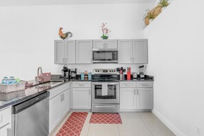 A modern kitchen with white cabinets, stainless steel appliances, and a red patterned rug. - Magical 4BR Home w/ Pvt Pool/ Spa Near Disney 128 (Kissimmee)