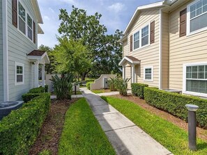 A residential street with two-story houses, a sidewalk, and well-maintained landscaping. - Spacious Family Retreat 4BDR near Disney - 2408 (Kissimmee)