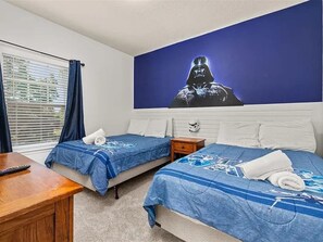 A hotel room with two beds, a desk, a window with curtains, and a wall with a Darth Vader poster. - Spacious Family Retreat 4BDR near Disney - 2408 (Kissimmee)