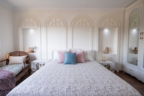 A bedroom with a large bed, a wooden chair, a nightstand, and a wardrobe. - Cairo Tower View 2-Bedroom Apartment In Tahrir Square (Cairo Governorate)