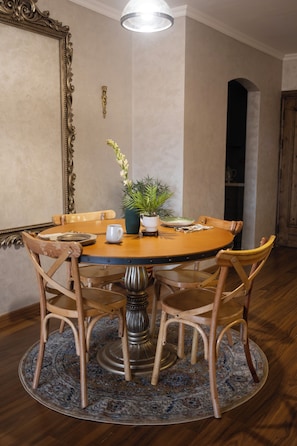 A dining room with a round table, wooden chairs, a vase with flowers, and a mirror on the wall. - Cairo Tower View 2-Bedroom Apartment In Tahrir Square (Cairo Governorate)