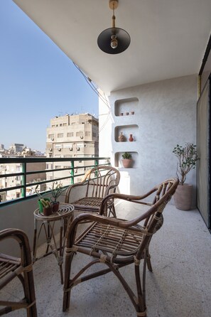 A balcony with wicker furniture, a small table, and potted plants. - Cairo Tower View 2-Bedroom Apartment In Tahrir Square (Cairo Governorate)