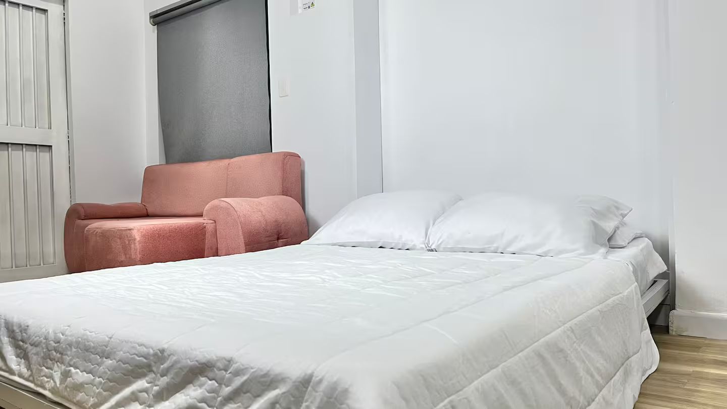 A bedroom with a bed, a chair, and a window.