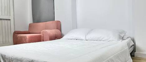 A bedroom with a bed, a chair, and a window.