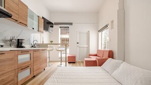 Un espacio habitable compacto con kitchenette, un sofá y una pequeña mesa.