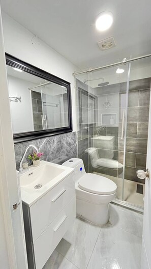 A modern bathroom with a glass shower enclosure, a white sink with a marble backsplash, and a toilet. - Moon house Modern Design, Comfortable & Elegant. (Cali)