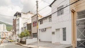 Vista de calle con edificios residenciales, una señal de tráfico indicando un límite de velocidad de 30 km/h y un poste de electricidad con cables aéreos.